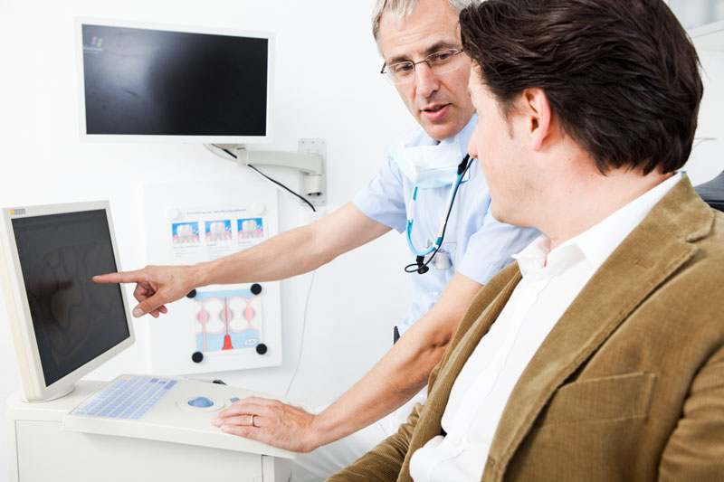 Dr. Wilmes erklärt einem Patienten am Bildschirm den digitalen Behandlungsplan für eine Cerec-Zahnkrone.