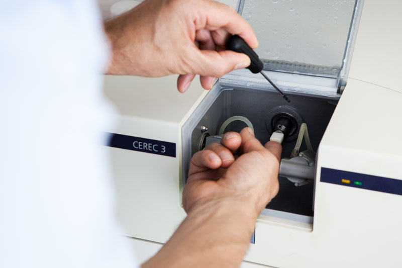 Nahaufnahme der CEREC 3-Fräseinheit, in der ein Zahnersatzstück automatisch aus einem Keramikblock gefräst wird.